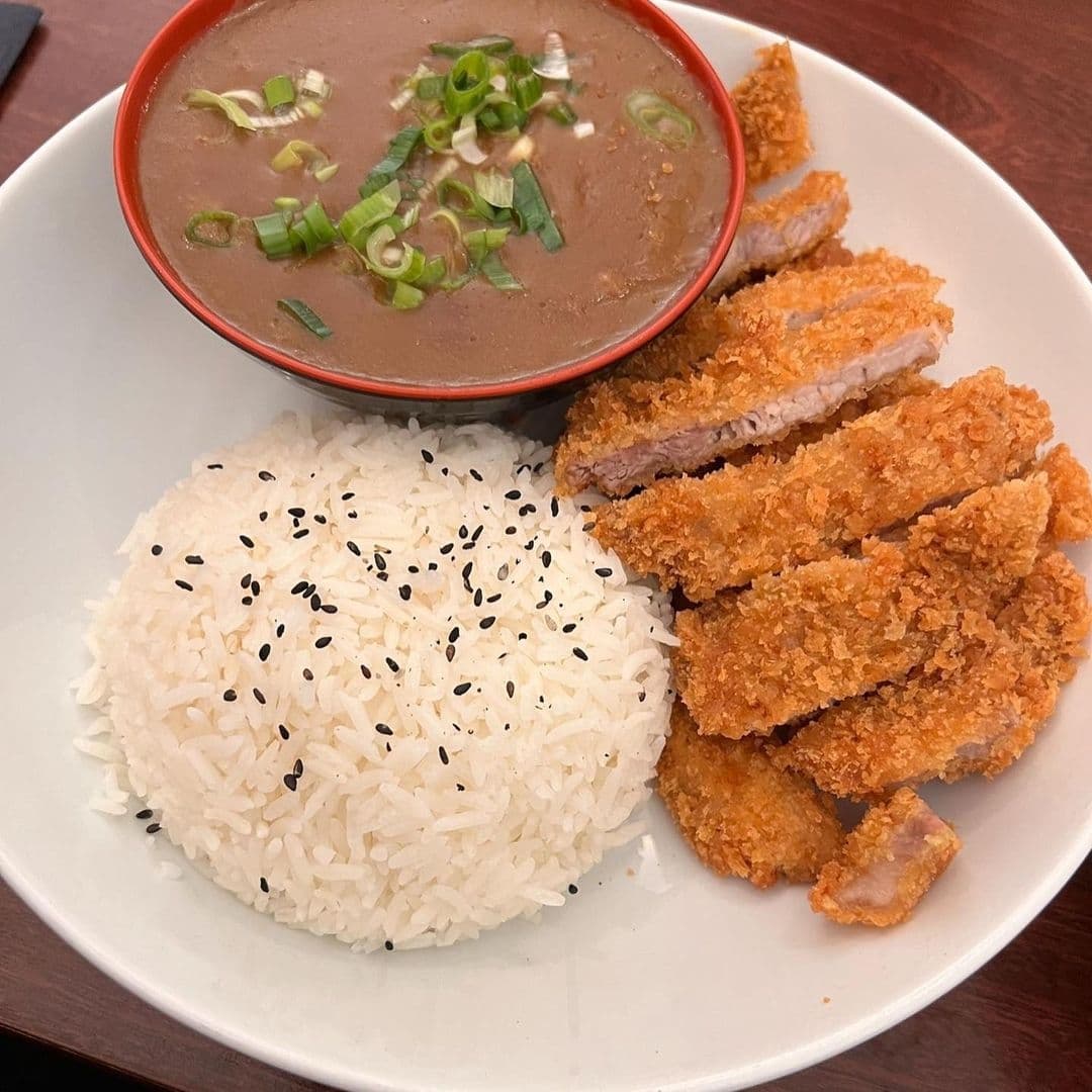 Alt text: "A plate of crispy tonkatsu (breaded pork cutlet) with a side of white rice sprinkled with black sesame seeds and a bowl of miso soup garnished with green onions at Fuji Hiro."