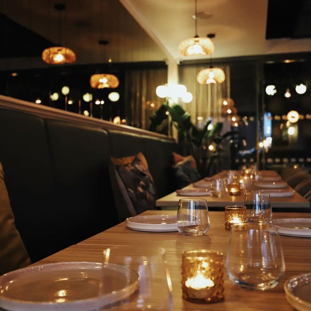 Elegant dining setup at Ma-Hé Coastal Indian with warm ambient lighting, neatly arranged tableware, and comfortable seating.