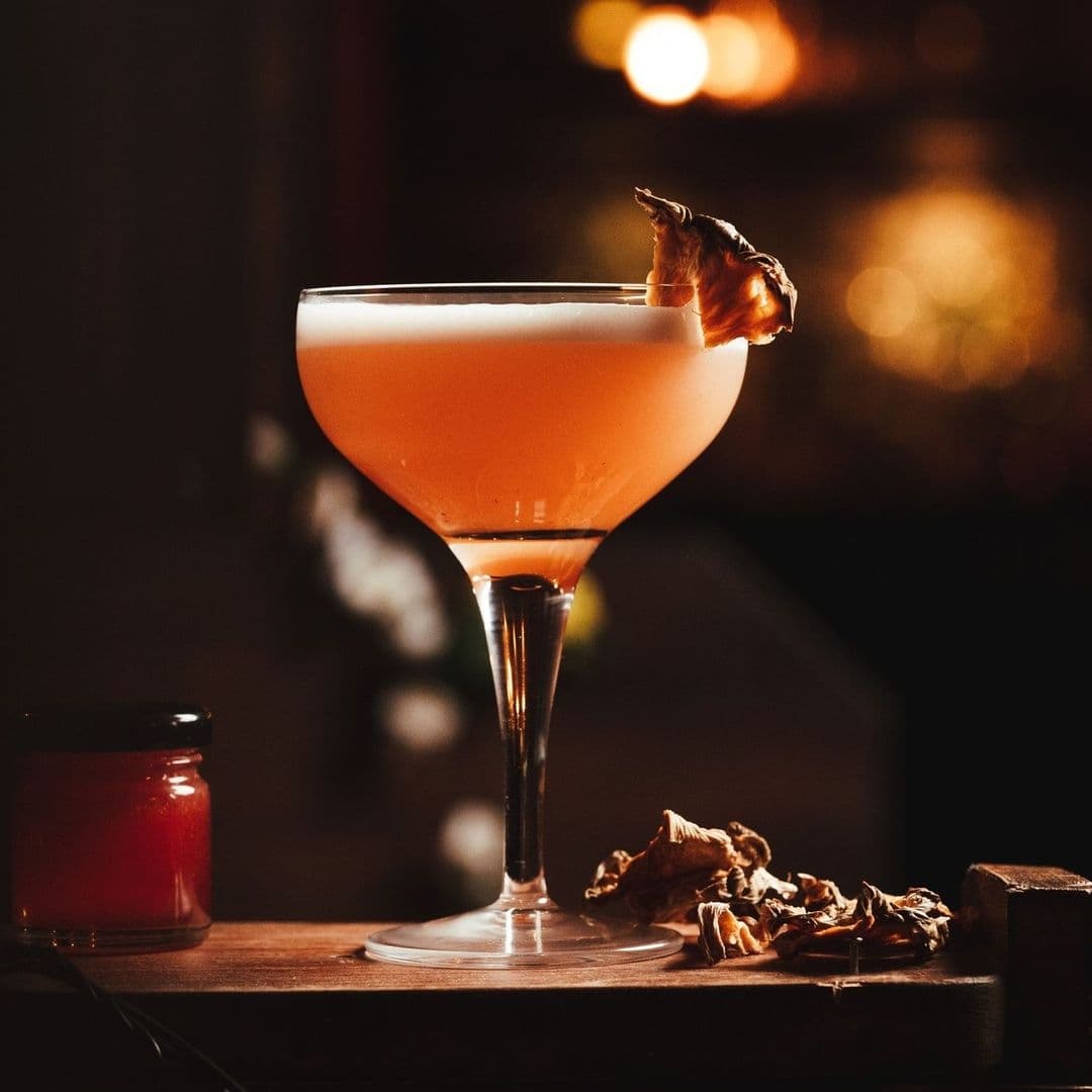 Elegant cocktail with a charred garnish in a martini glass at Smokestack, evoking a warm and sophisticated ambiance.