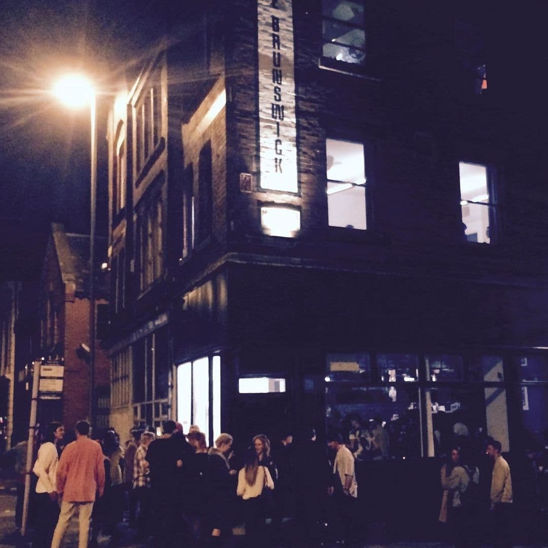 Nighttime outside The Brunswick with illuminated signage and people gathered on the sidewalk.