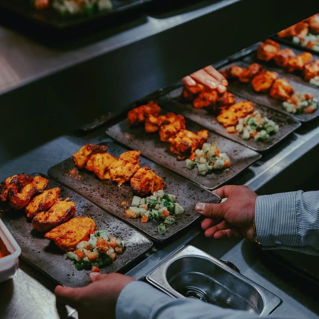 Alt text: "A selection of grilled meats and diced vegetables on slate plates at Dastaan, ready to be served."