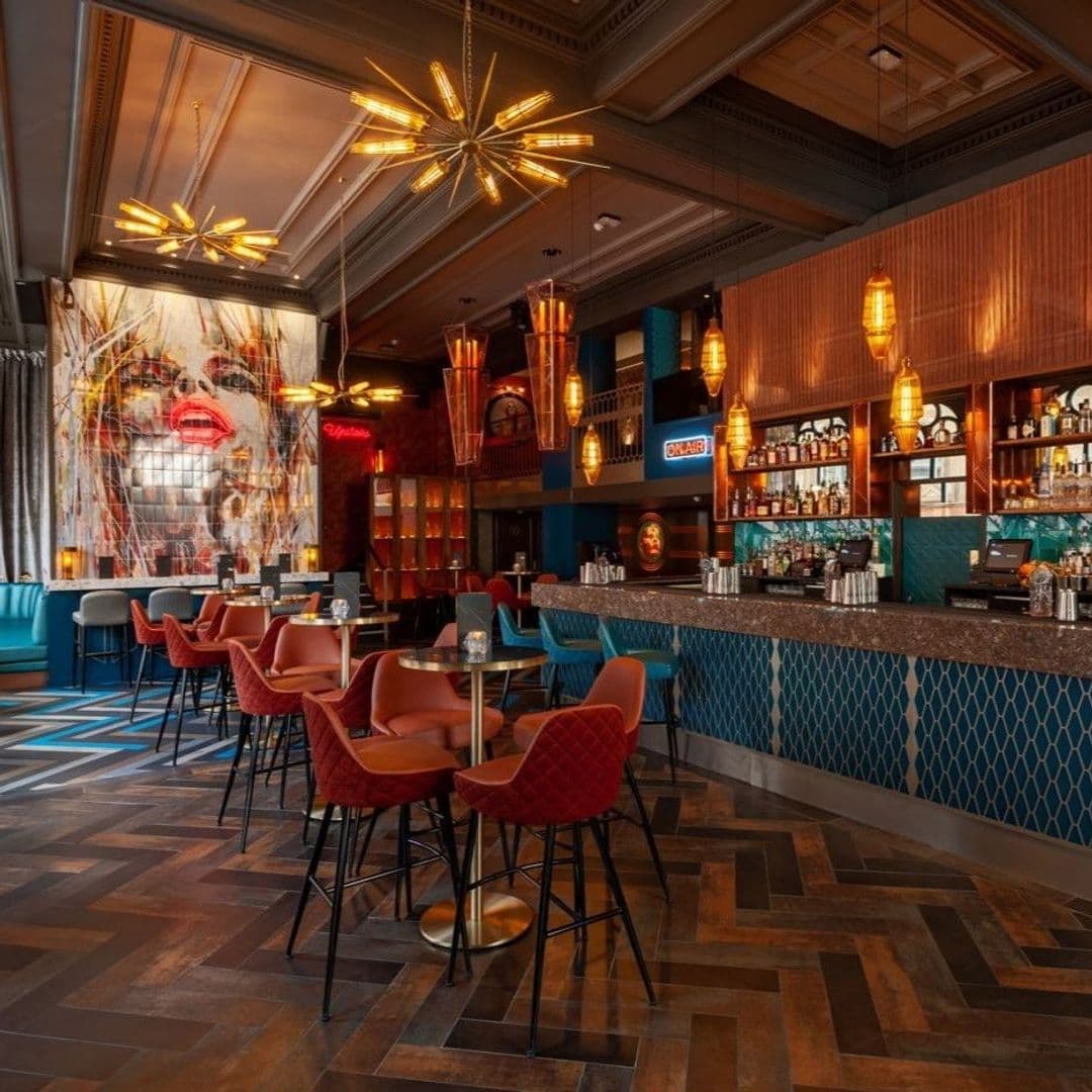 Interior of Dirty Martini featuring stylish bar area with eclectic decor, starburst chandeliers, plush seating, and vibrant mural.