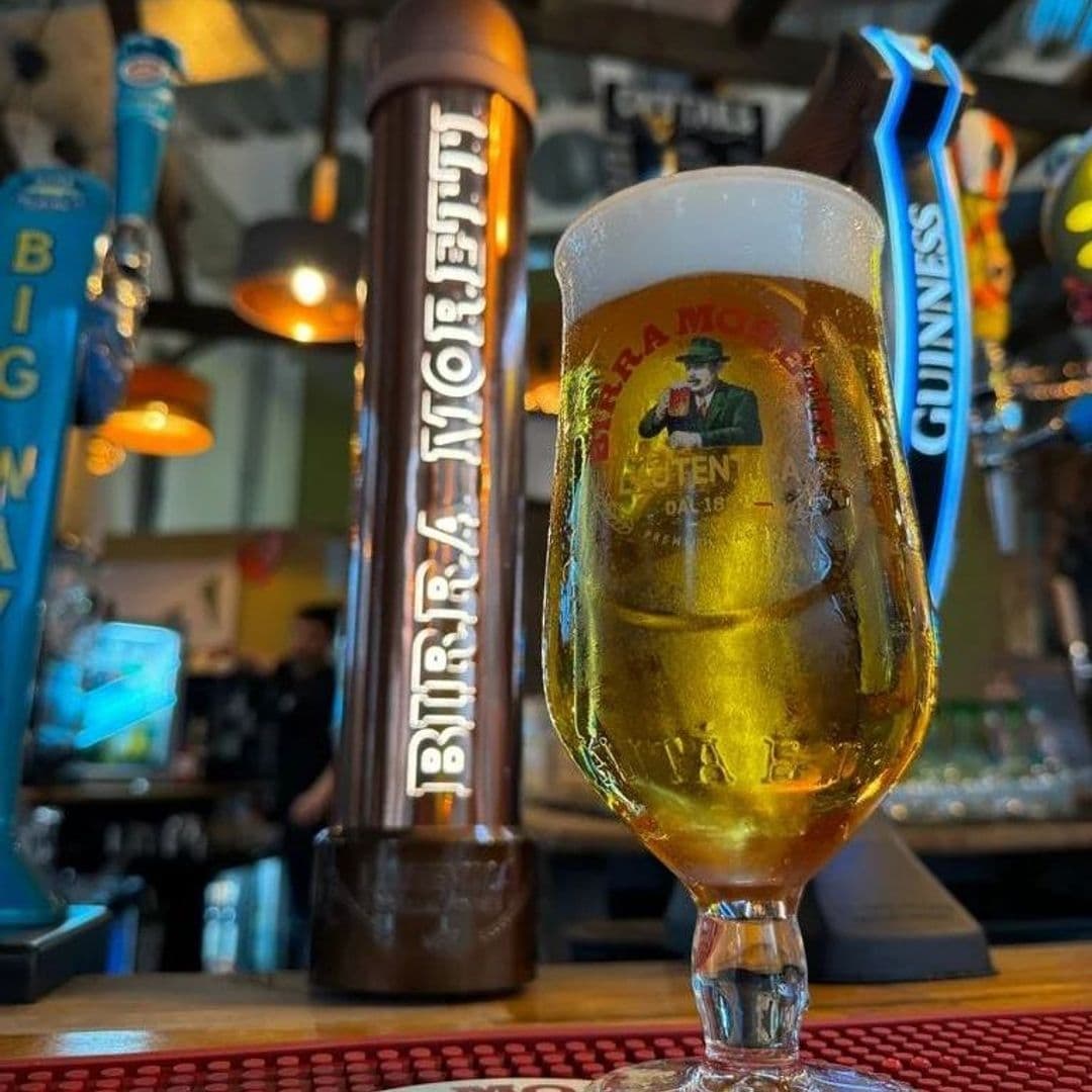 Close-up of a cold beer in a glass with the logo "Birra Moretti" at Hoist House, with other beer taps in the background and a blurred bar setting.