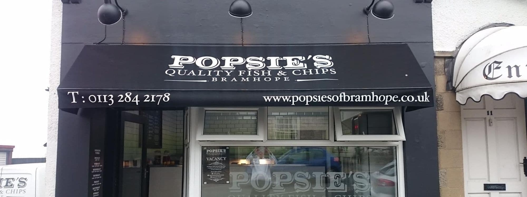 Exterior view of Popsie's Quality Fish & Chips in Bramhope, showcasing the shop's signage with contact details and website.