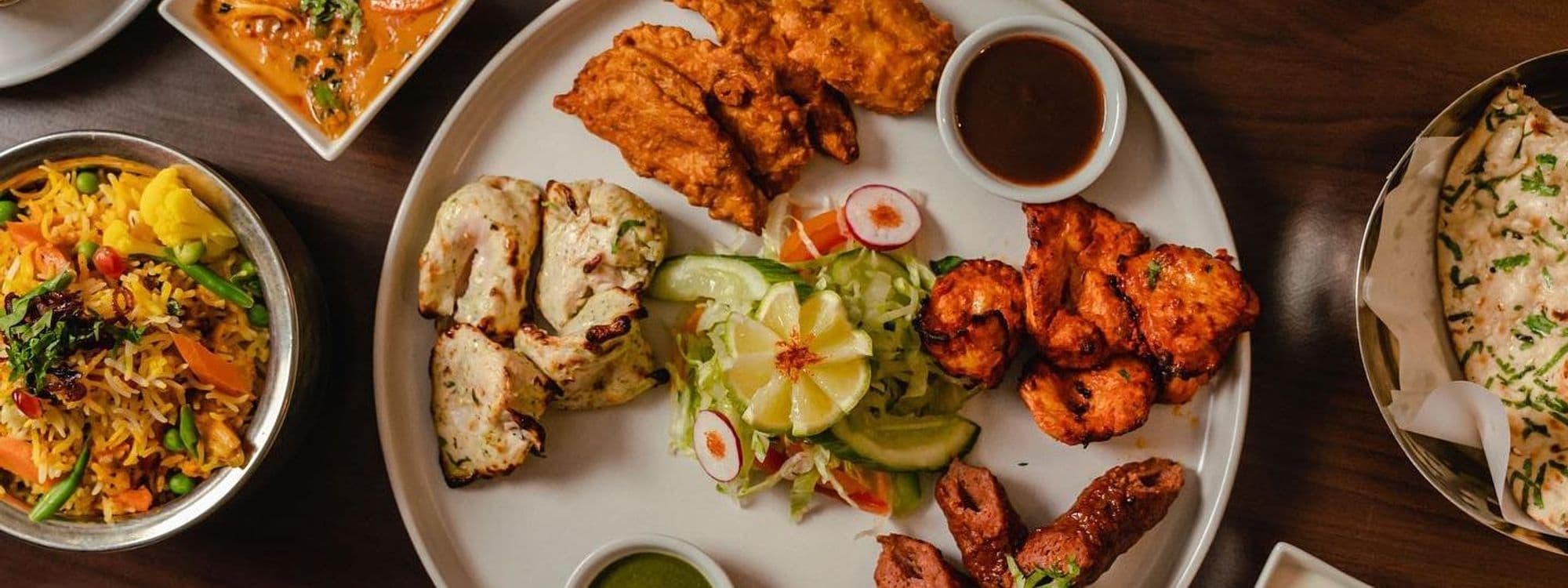 Assorted Indian cuisine dishes on a table at Rasoi Stories, featuring biryani, curry, grilled meats, and naan bread.