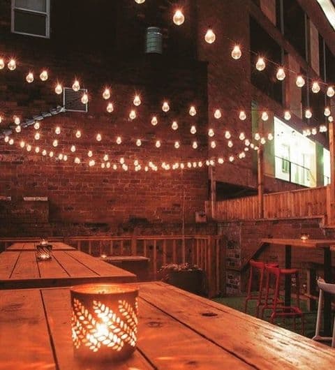 Cozy evening ambiance at Roland's with string lights over wooden tables and a lit candle centerpiece.