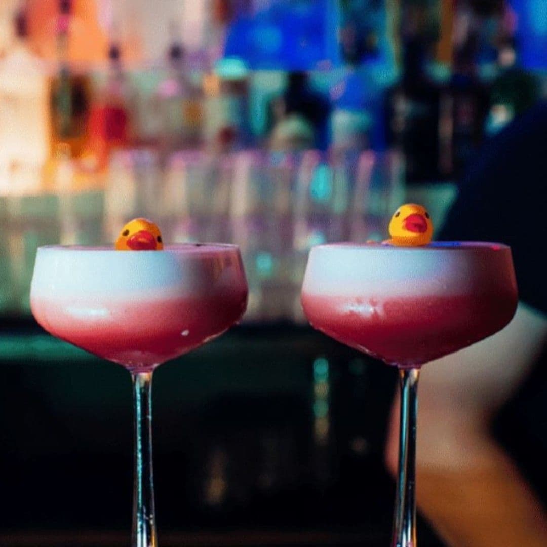 Two pink frothy cocktails with miniature rubber ducks garnishing the rim, served at Cuckoo.