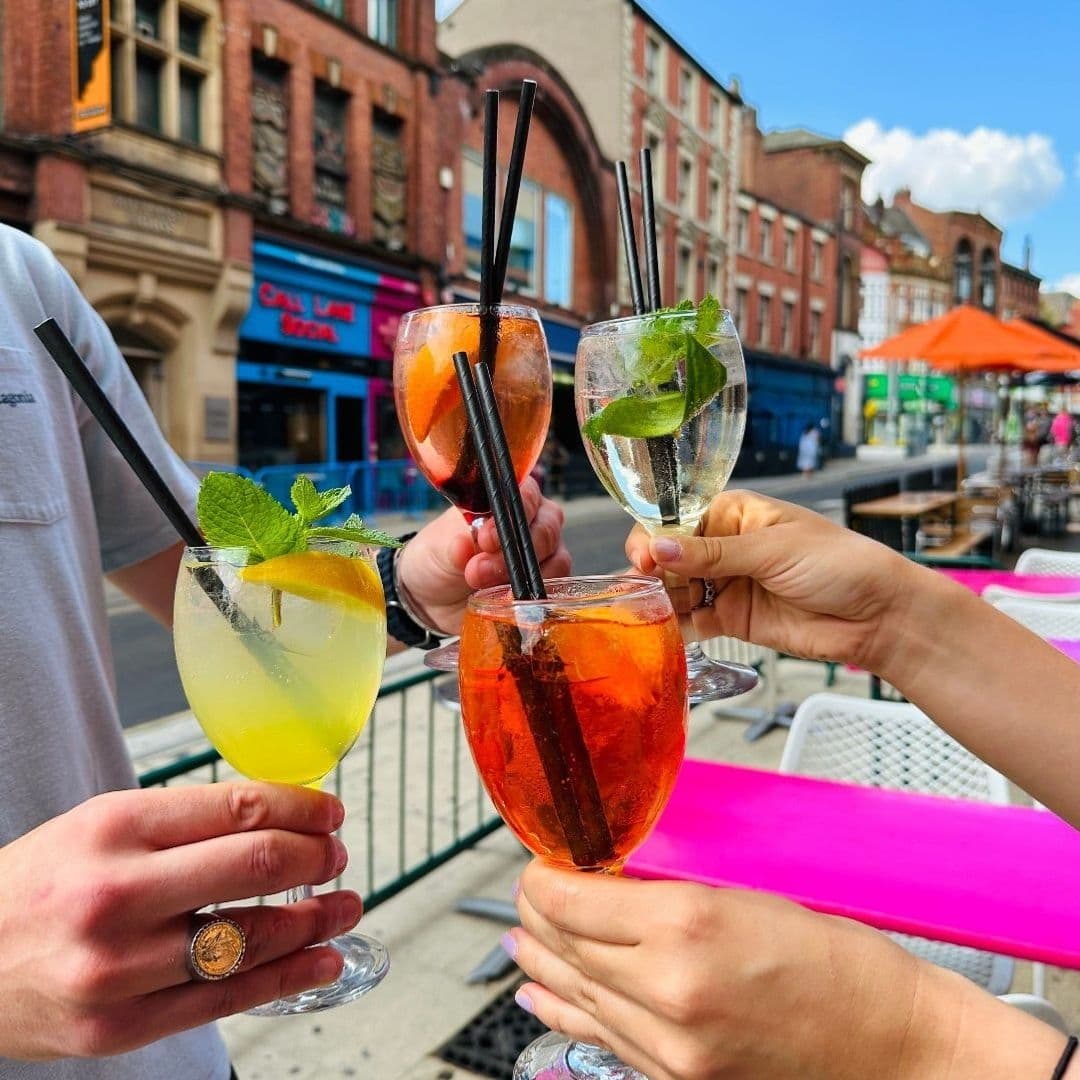 People toasting with colorful cocktails on a sunny day at Cuckoo.