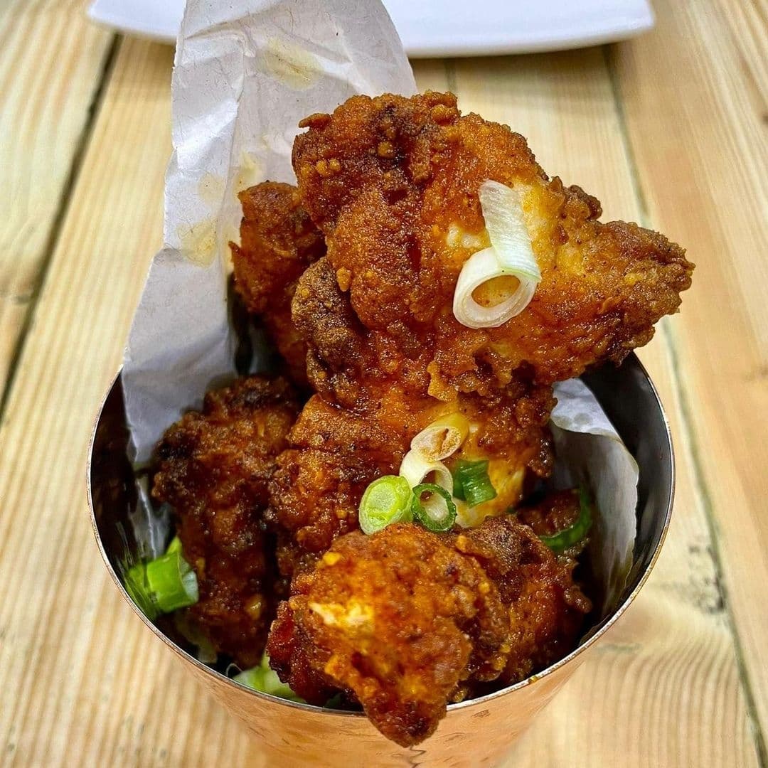 Crispy fried chicken pieces garnished with green onions served in a metal container at Ecco Pizzeria.