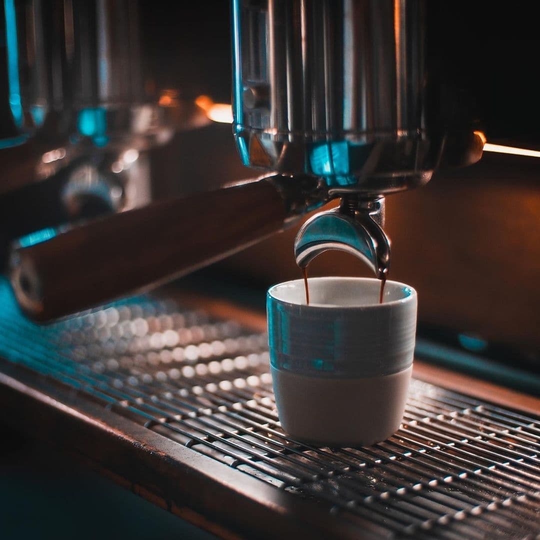 Espresso being freshly brewed into a white ceramic cup at Mrs Atha's coffee shop, with a focus on the pouring from the espresso machine's spout.