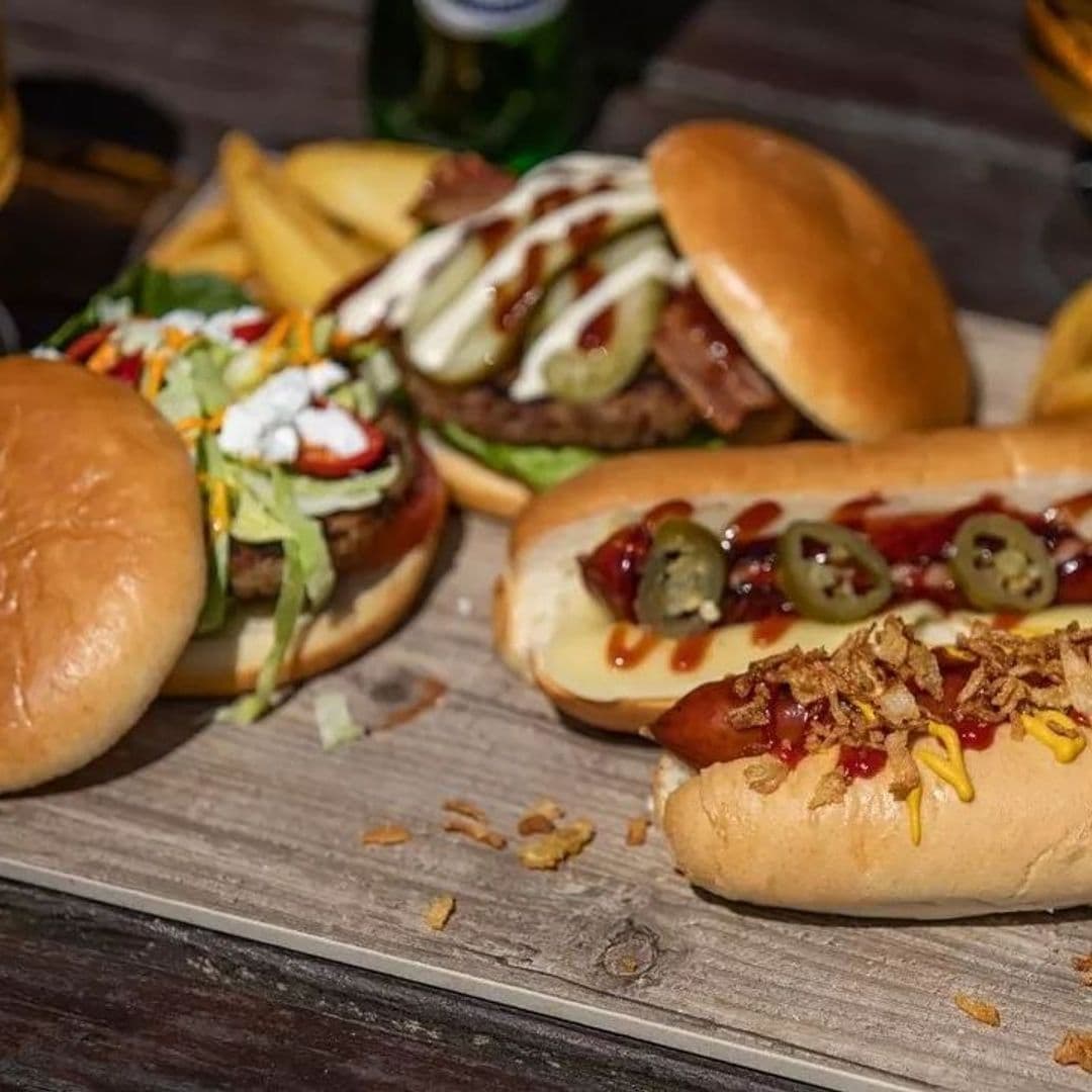 Mouthwatering selection of pub food at Parkside Tavern, featuring a juicy burger with toppings, hot dogs with condiments, and a side of golden fries.