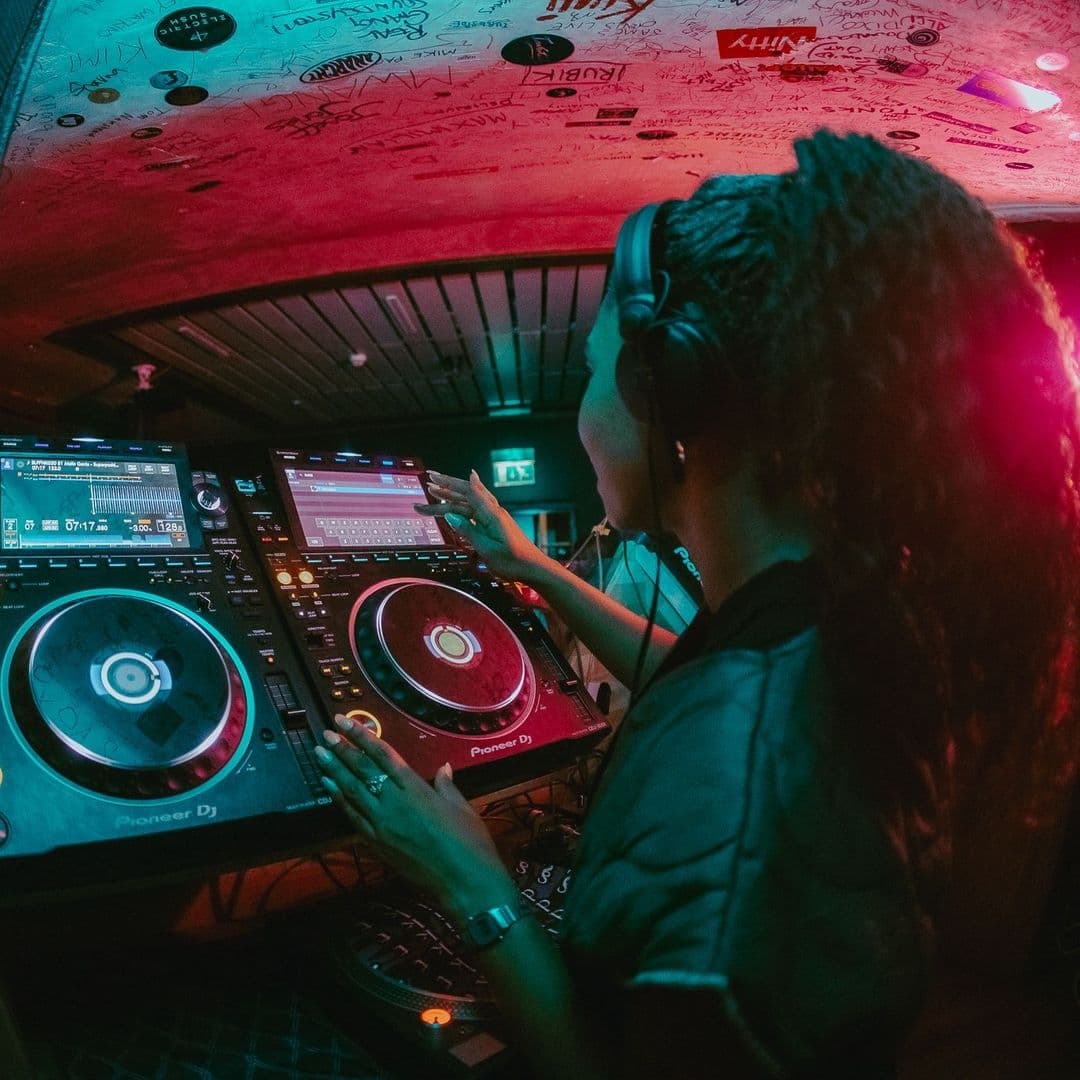Female DJ mixing music at Distrikt nightclub with colorful lighting and graffiti-covered walls.