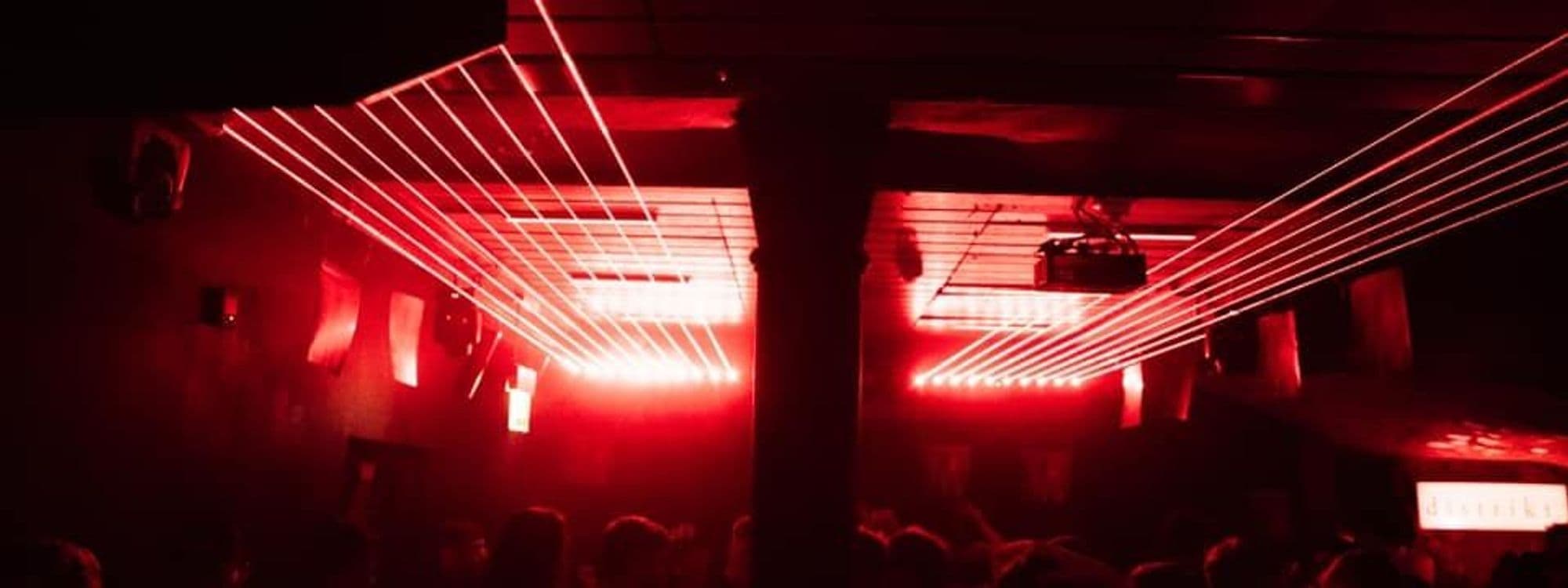 Vibrant nightlife scene at Distrikt with red neon lights and silhouettes of people enjoying the party atmosphere.
