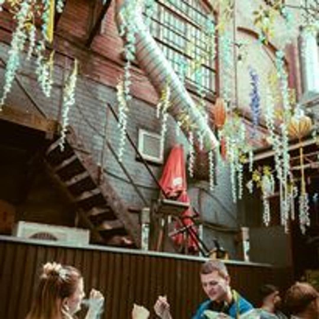 Visitors enjoying the vibrant atmosphere at Distrikt with colorful hanging decorations and an outdoor seating area.