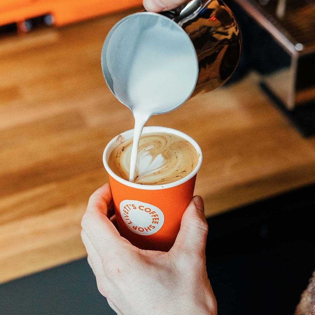Barista pouring milk into a coffee cup creating latte art at Livett's Coffee Shop.