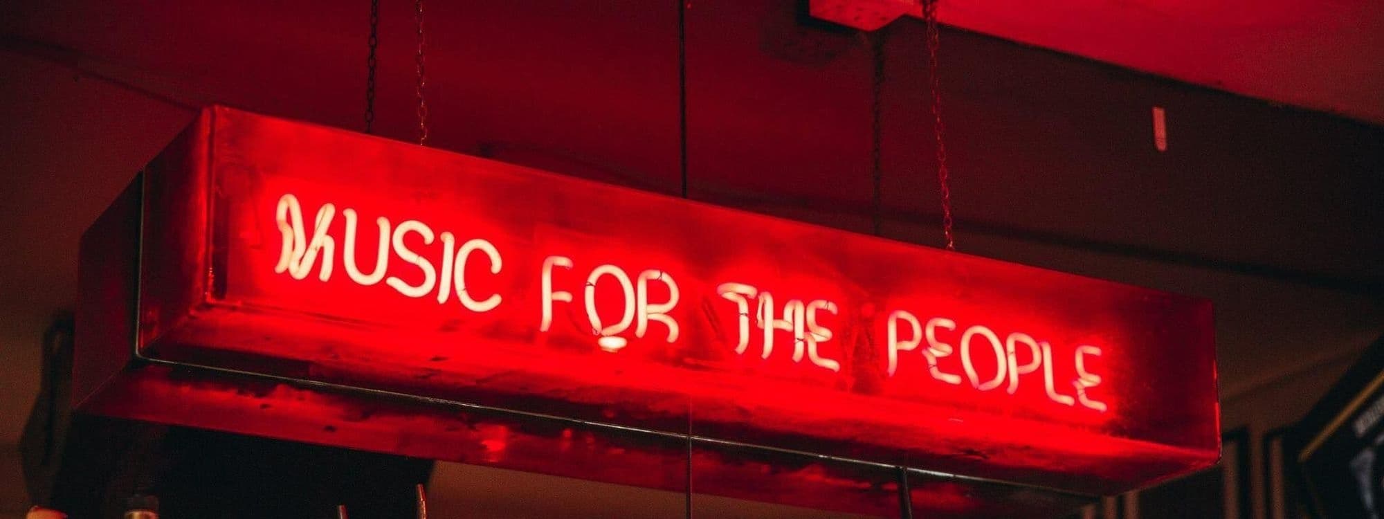 Red neon sign reading 'Music for the People' at MOJO.