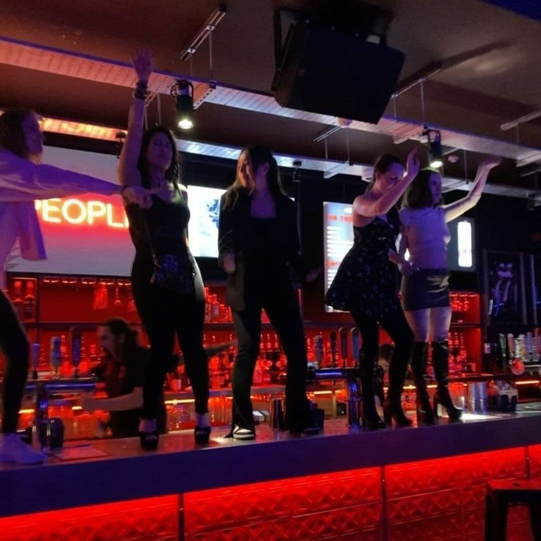 Group of people dancing on a bar counter under dim lighting at MOJO nightclub.