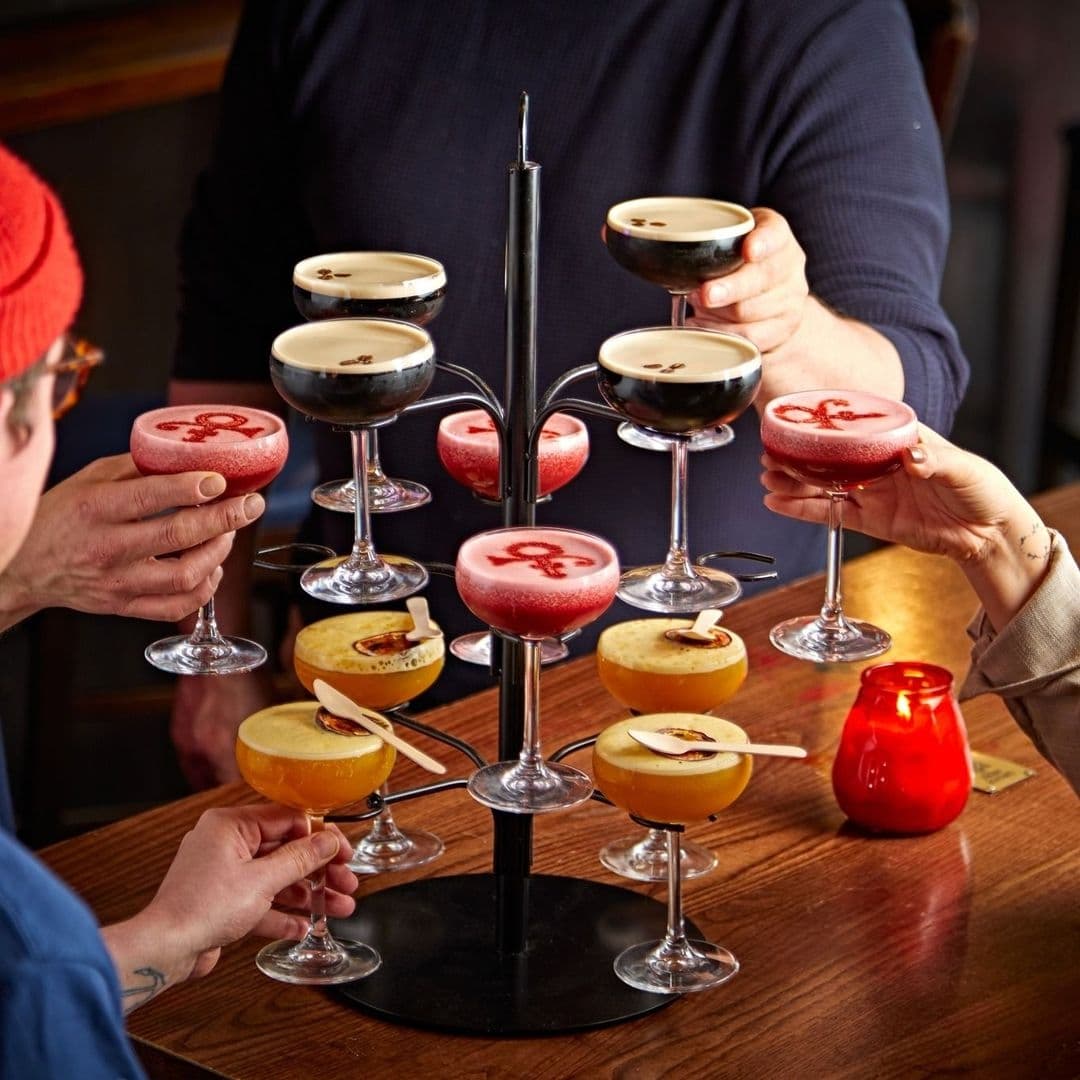 Patrons enjoying a variety of cocktails on a multi-tiered serving stand at MOJO.