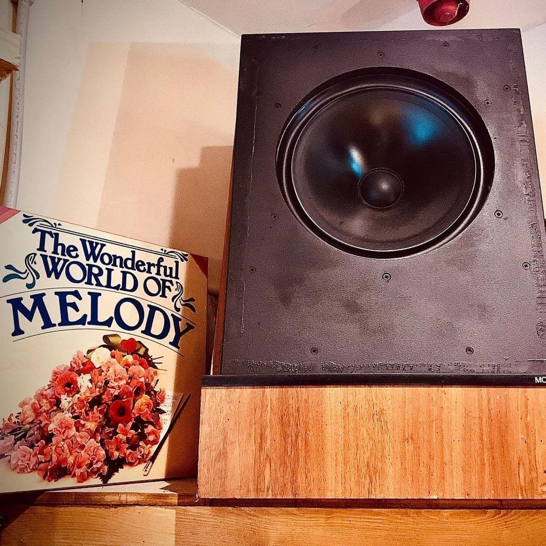 Vintage black speaker on a wooden shelf with a decorative album cover titled "The Wonderful World of Melody" at Melodie 71.