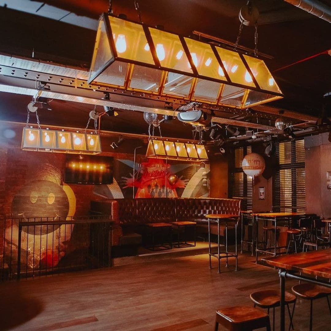Interior of Ten Bar featuring warm lighting, leather seating, and a vibrant mural on the brick wall.