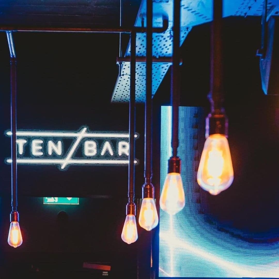 Illuminated 'Ten Bar' neon sign with glowing filament light bulbs in the foreground, creating an inviting ambiance.