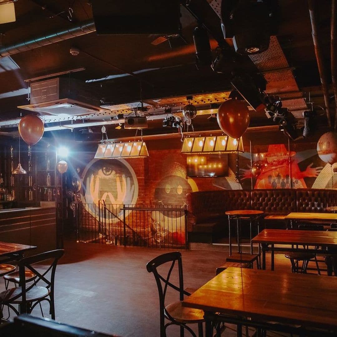 Interior of Ten Bar with warm lighting, exposed brick walls adorned with eye-catching murals, comfortable seating, and a relaxed atmosphere.