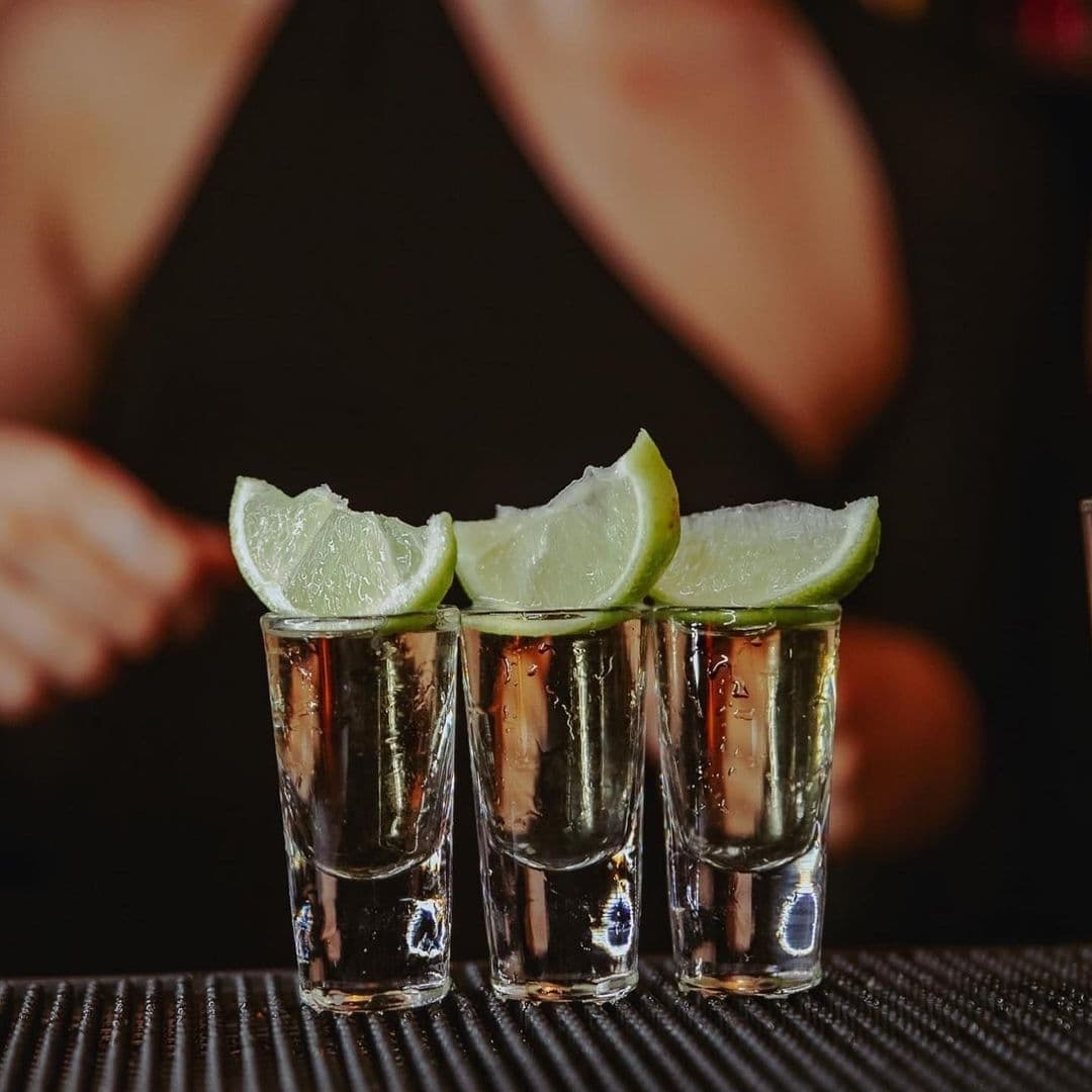Three tequila shots with lime wedges on top, served on a bar counter at Ten Bar.