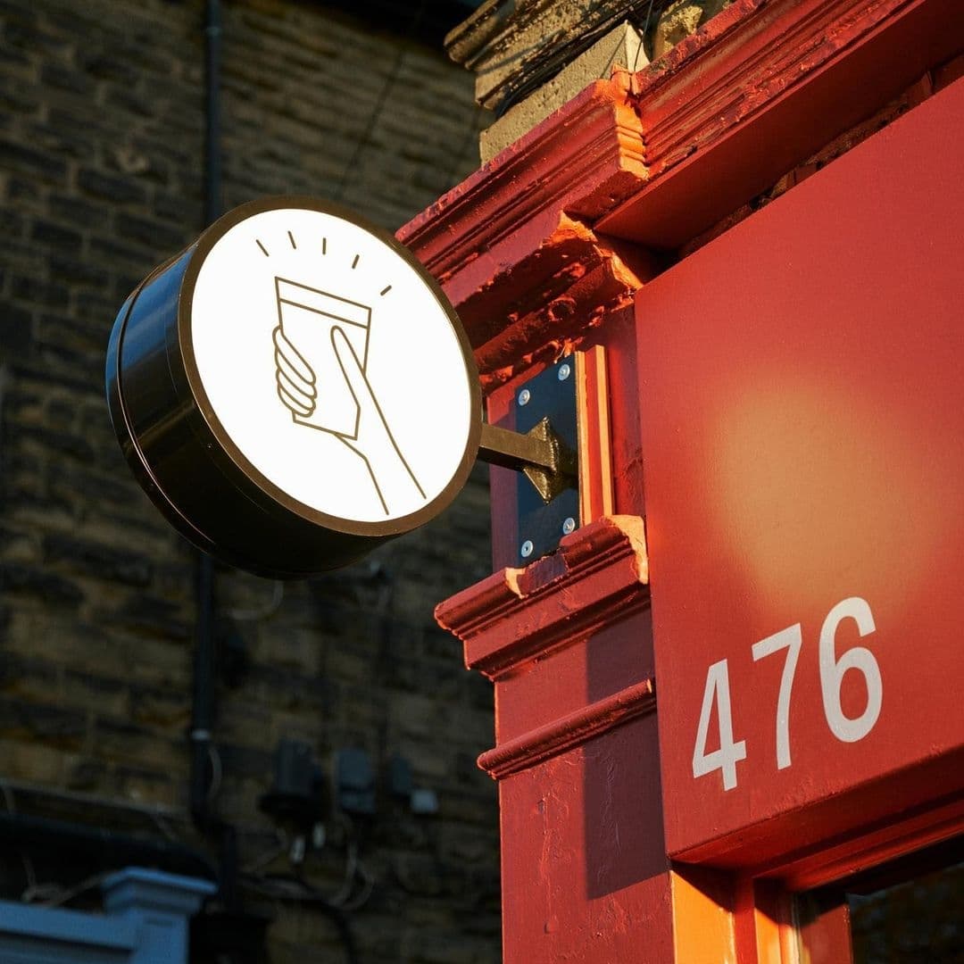Sign with a raised glass icon outside The Melbourne at address number 476, indicating a place for drinks or social gathering.