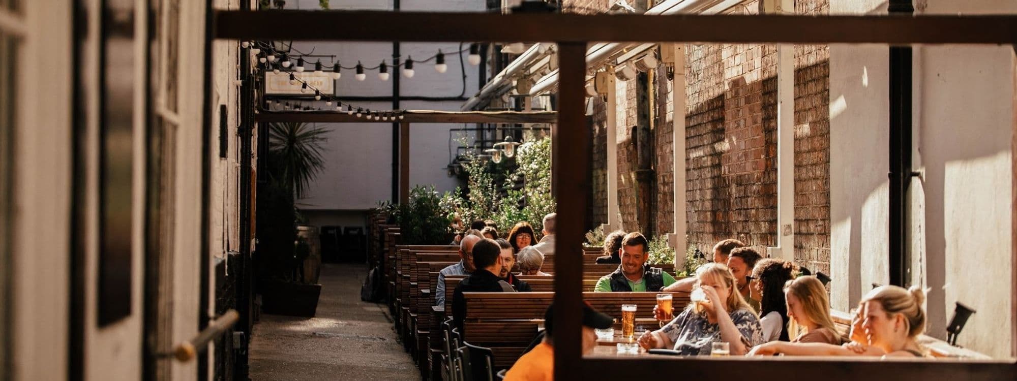 Outdoor seating area at The Turk's Head with people enjoying drinks and conversation under string lights.
