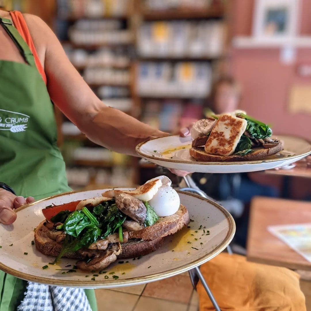 Waitstaff serving gourmet sandwiches on plates at Crust & Crumb, with a focus on fresh ingredients and a cozy dining atmosphere.