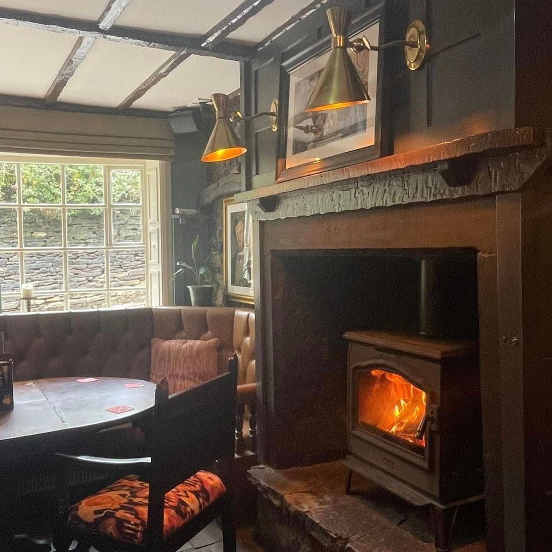 Cozy interior of Bankhouse Inn with warm lighting, a lit fireplace, comfortable seating, and framed pictures on the wall.