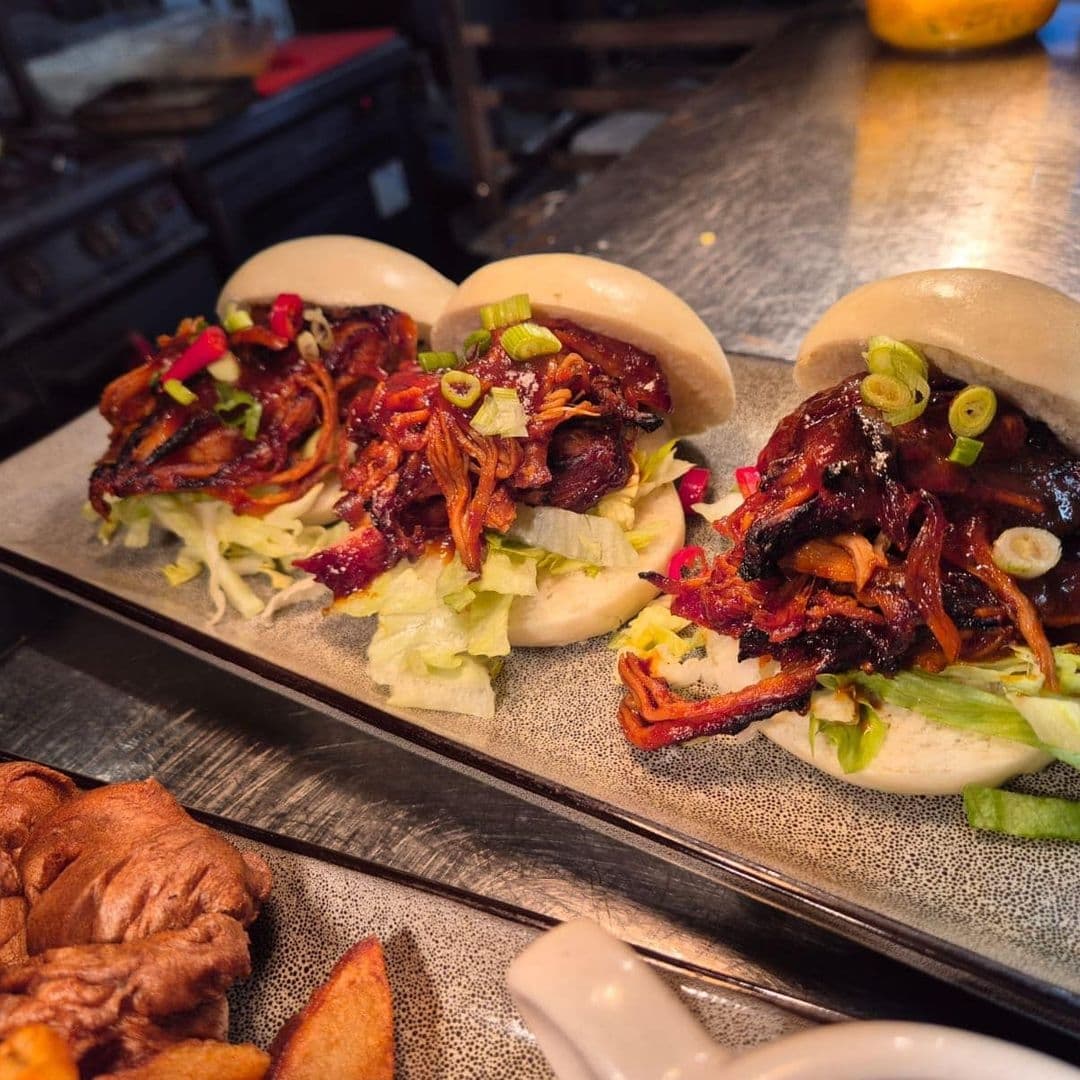 Gourmet pulled pork sliders with fresh garnishes on a serving tray at Bankhouse Inn.