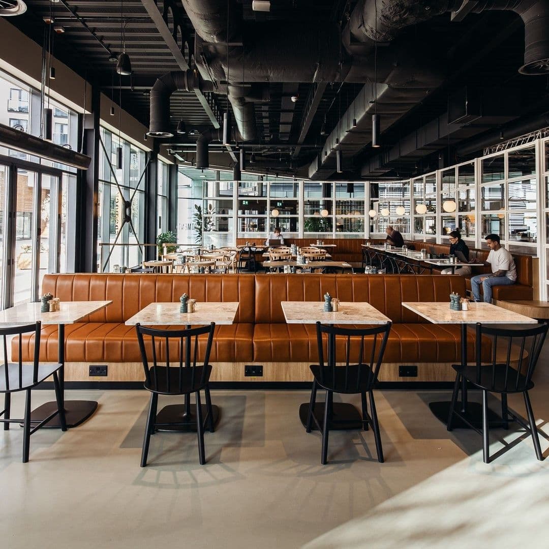 Interior of Fearns Dock restaurant with modern decor, featuring wooden tables, leather booth seating, and patrons enjoying the ambiance.