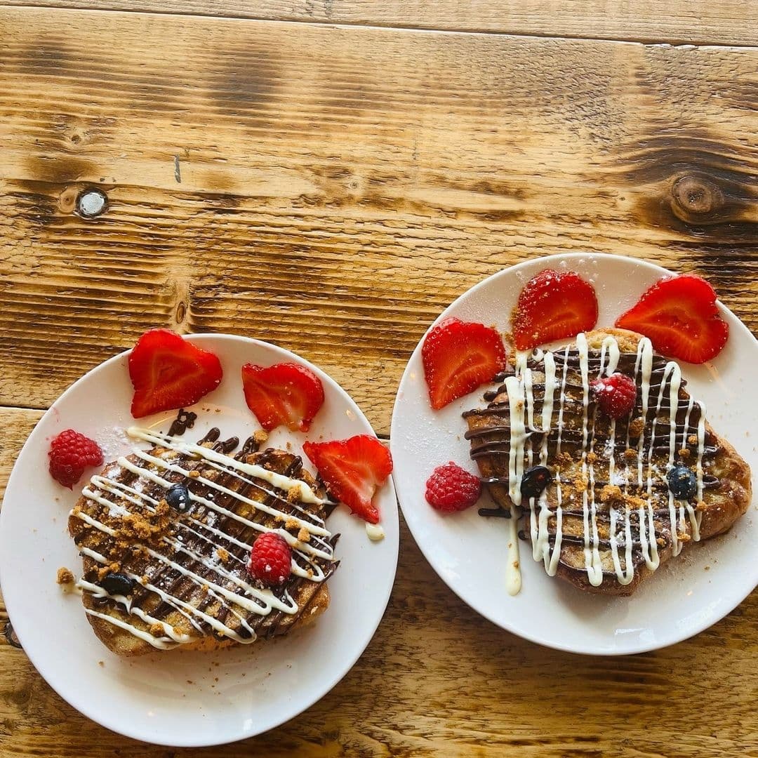 Delicious breakfast pastries topped with fresh berries and drizzled with white icing, served on white plates at Forista.