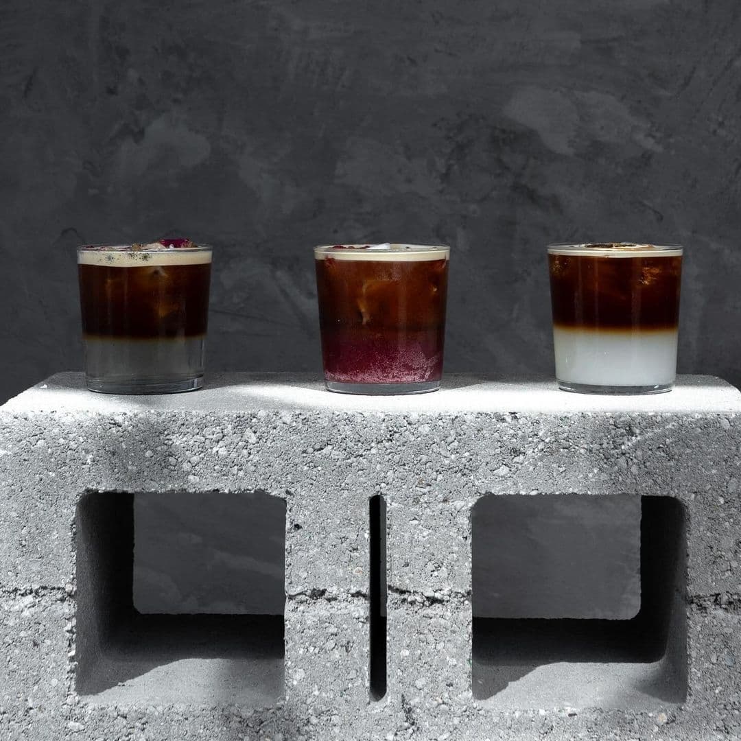 Three different styles of cold coffee beverages presented on a concrete block at Raw Coffee, showcasing the unique and artisanal coffee offerings available for visitors.