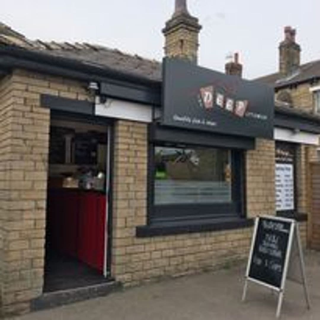 Exterior view of The Deep – Pudsey, showcasing the entrance with an open door, a black signboard with the establishment's logo, and a chalkboard menu on the sidewalk.