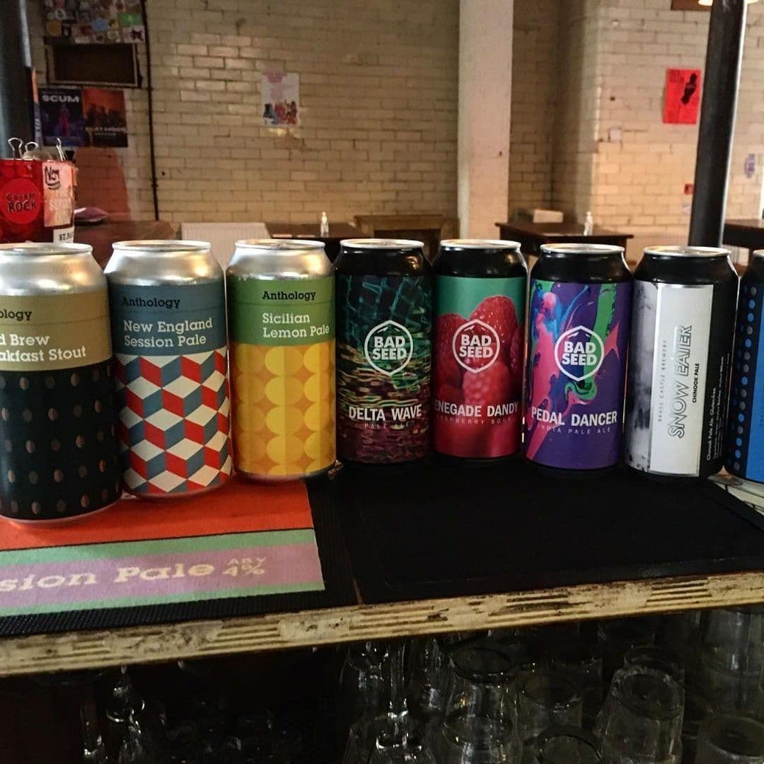 "Assorted craft beer cans on a bar at Wharf Chambers, showcasing local brews with colorful labels."