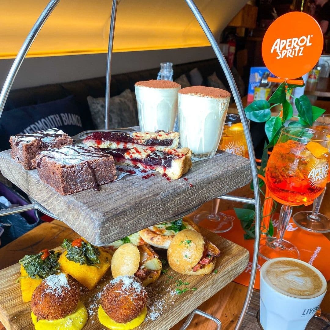 Delicious Italian appetizers and drinks served at LIVIN'Italy, featuring a selection of pastries, sandwiches, and Aperol Spritz cocktails.