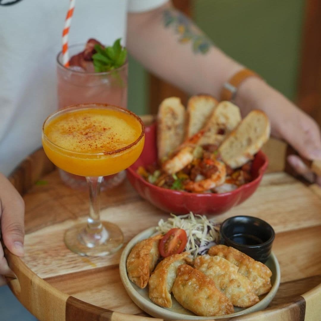 Alt text: "Savor the flavors of OHANA with a colorful array of dishes and drinks, featuring a margarita with a spiced rim, a refreshing cocktail, and a variety of appetizers including dumplings and a shrimp salad with toasted bread."