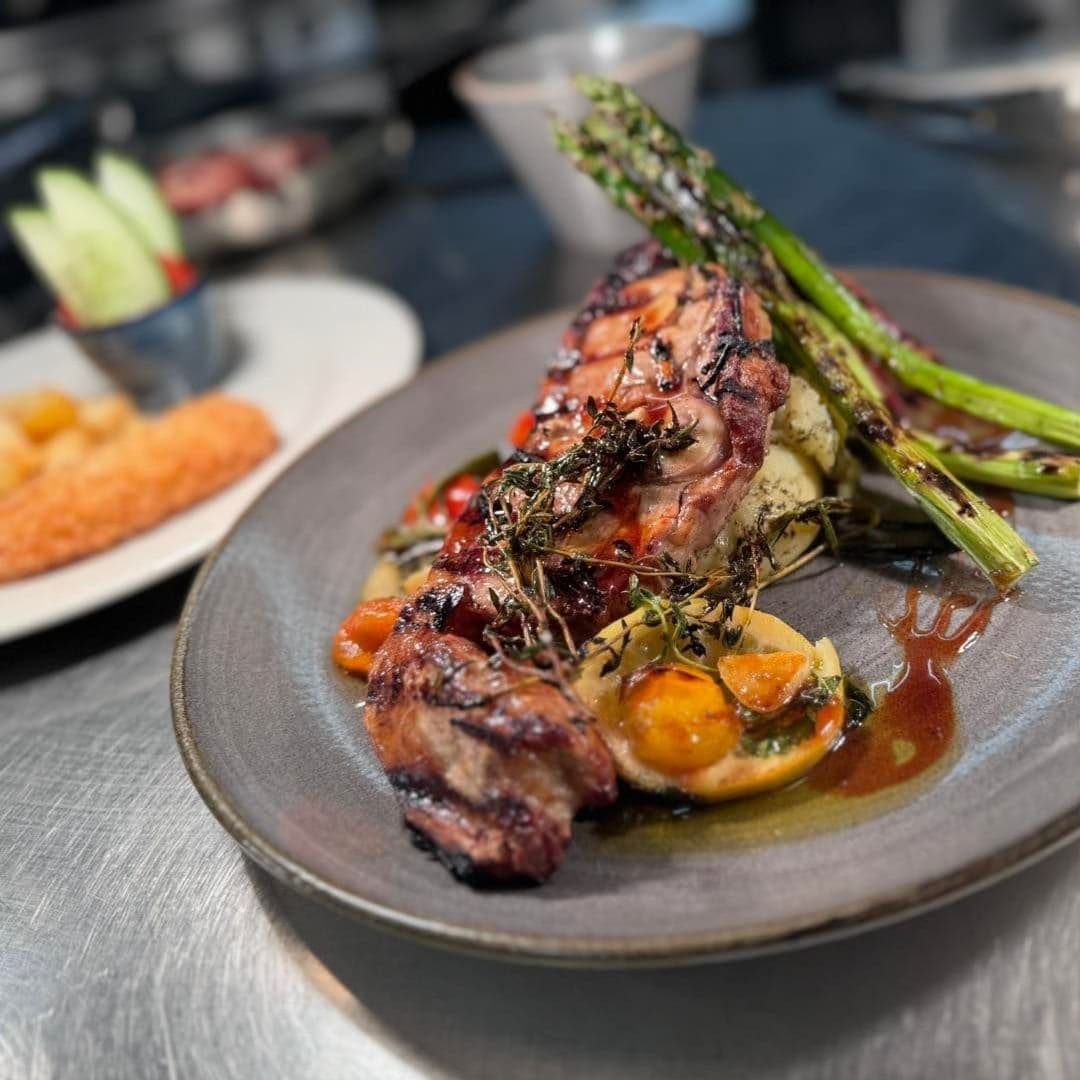 Grilled steak with herbs, asparagus, and roasted vegetables served on a ceramic plate at Scotts Arms.