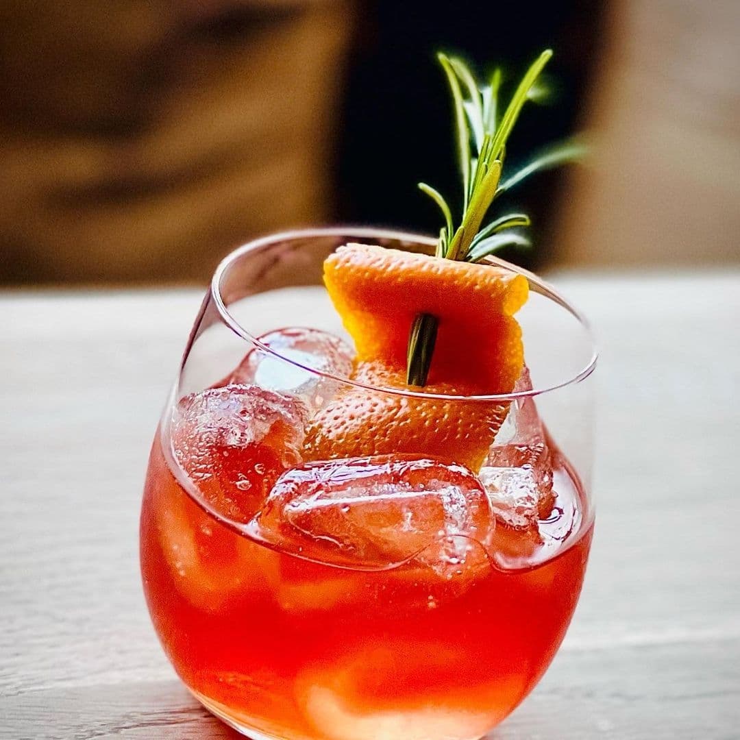 Refreshing cocktail with ice, orange peel, and rosemary garnish served at The Chequers Inn.