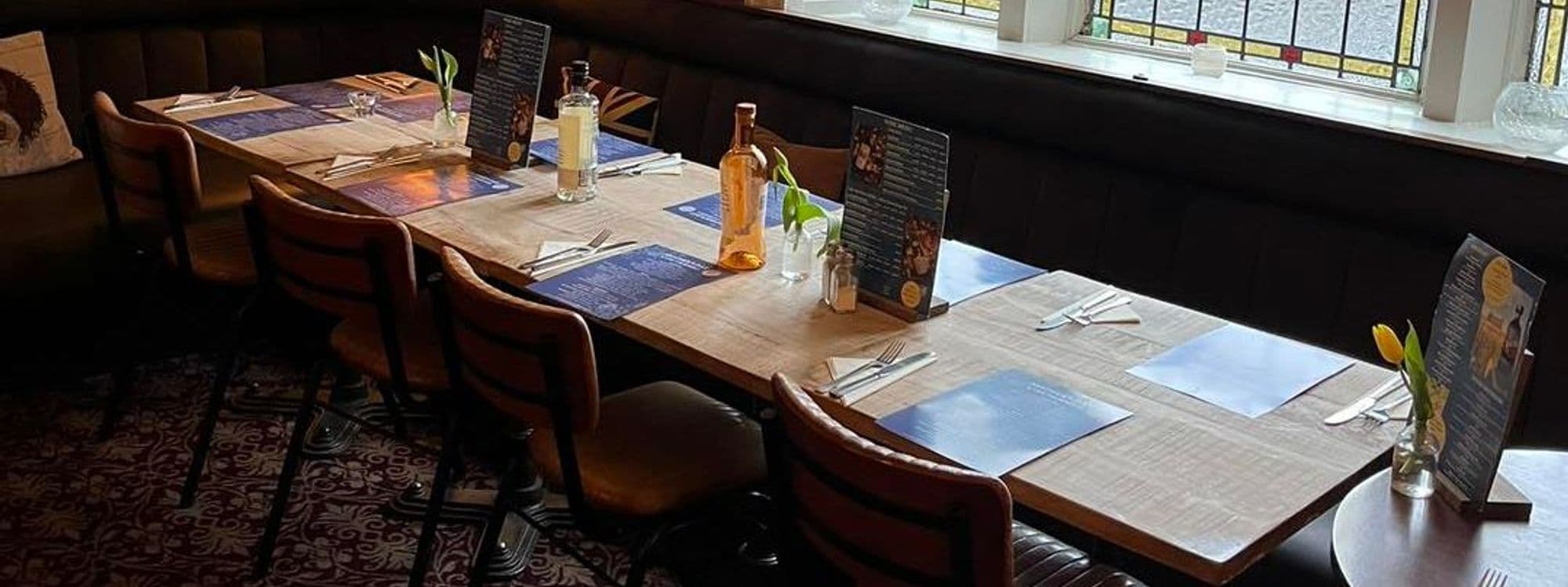 Wooden dining table set for guests with menus and cutlery at The Thornhill.