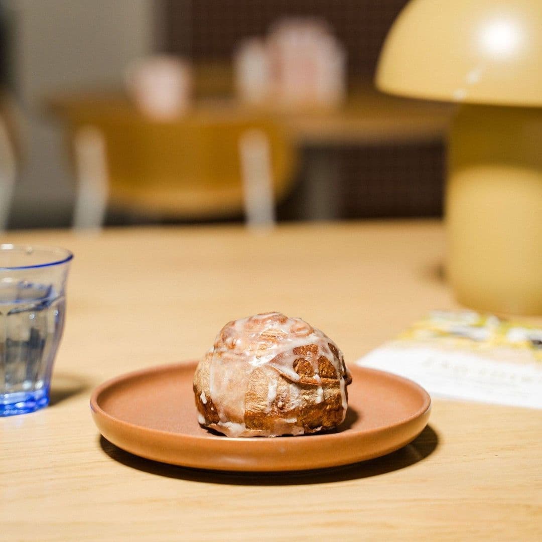 Freshly baked pastry on a ceramic plate at Galleria, with a glass of water and cozy cafe ambiance in the background.
