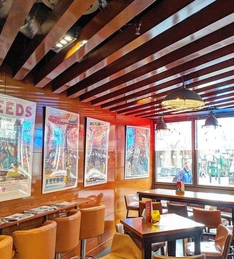 Interior of Tapped brewpub with wooden tables and chairs, colorful pinball machine artwork on the walls, and a view of the street through the window.
