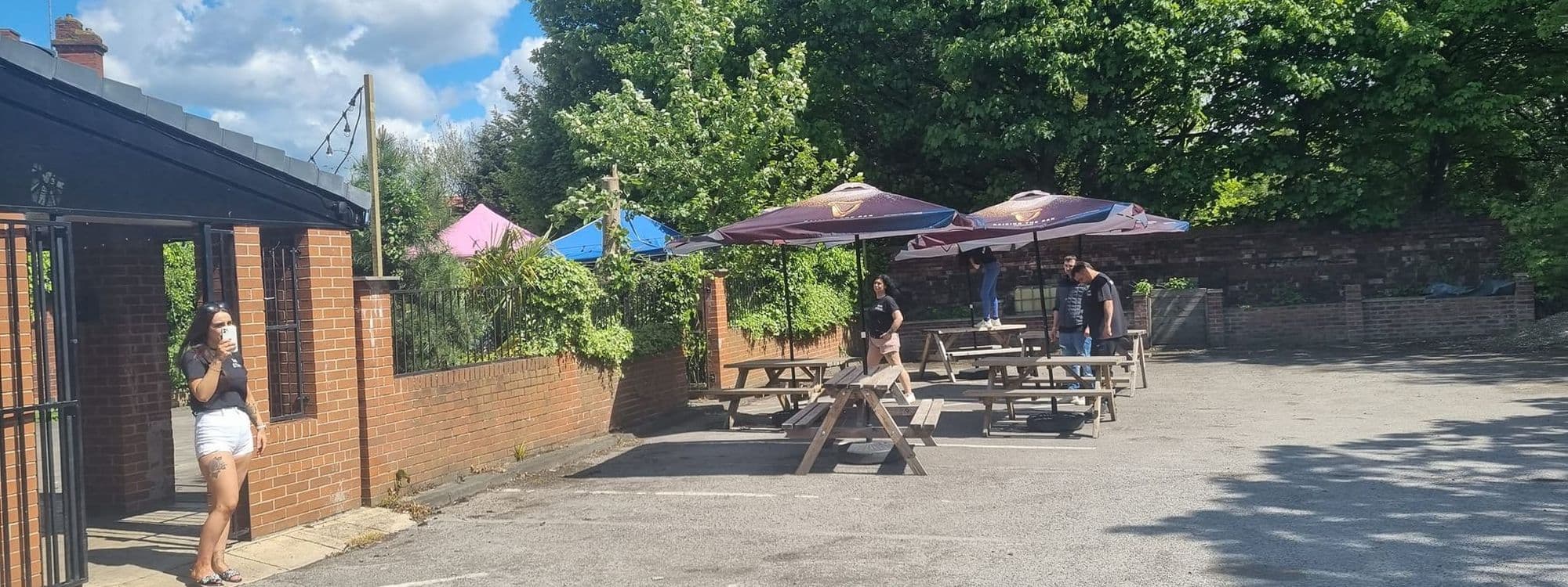 Outdoor seating area at Parnaby Tavern with patrons and colorful umbrellas on a sunny day.