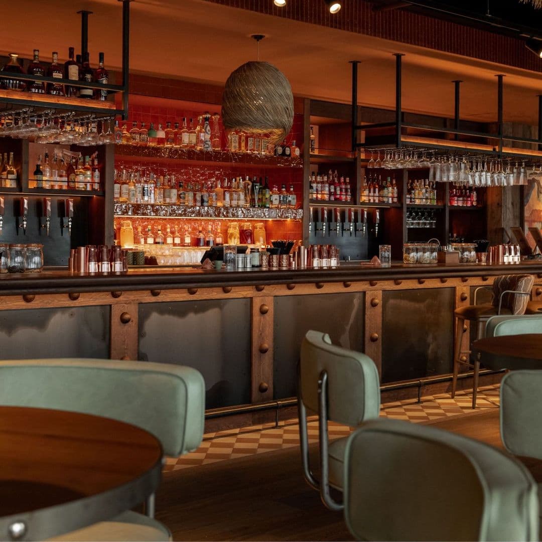 Alt text: Interior view of Azotea, featuring a stylish bar with a variety of bottles on shelves, modern seating, and warm lighting.