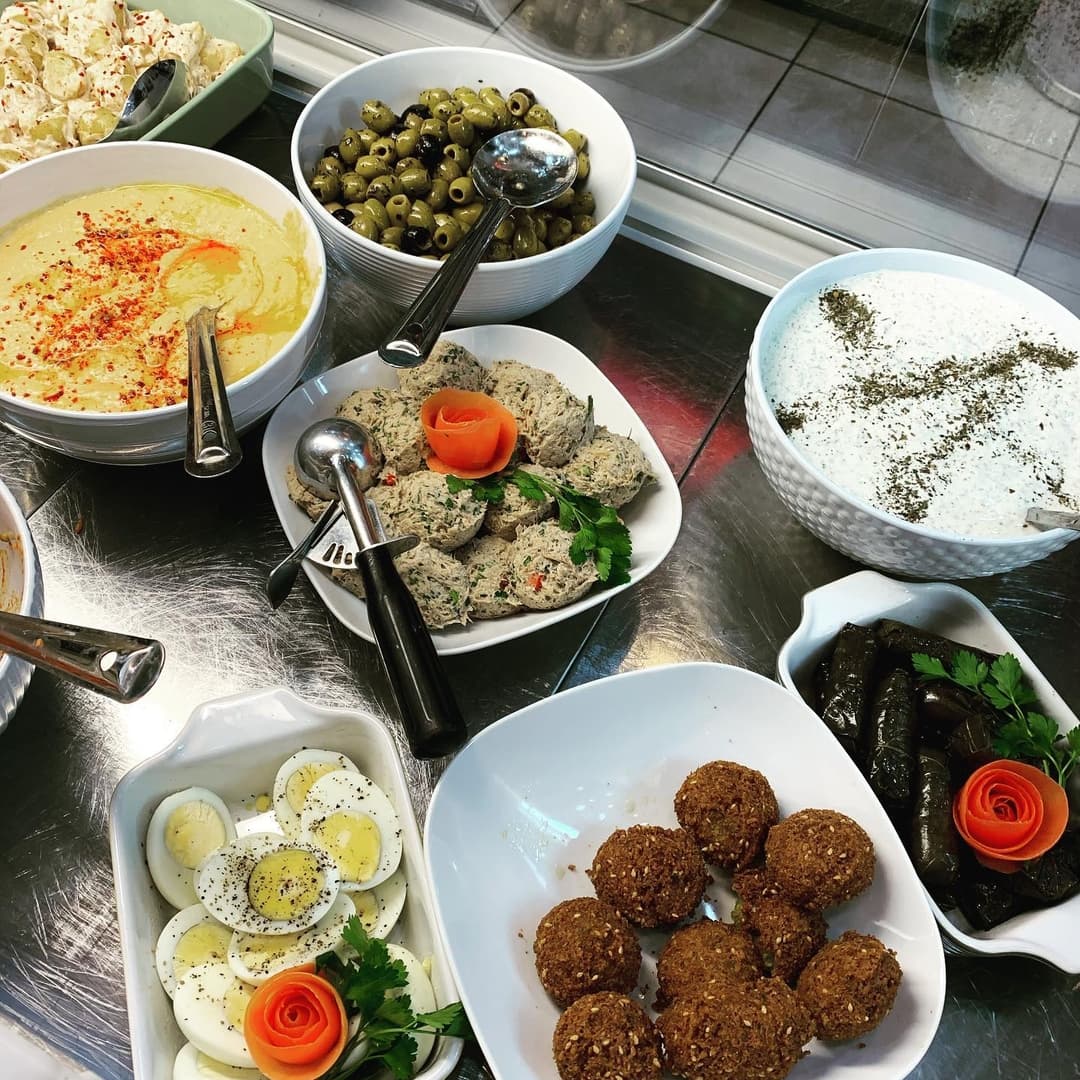 A vibrant spread of Mediterranean dishes, including hummus, olives, stuffed grape leaves, and colorful garnishes.