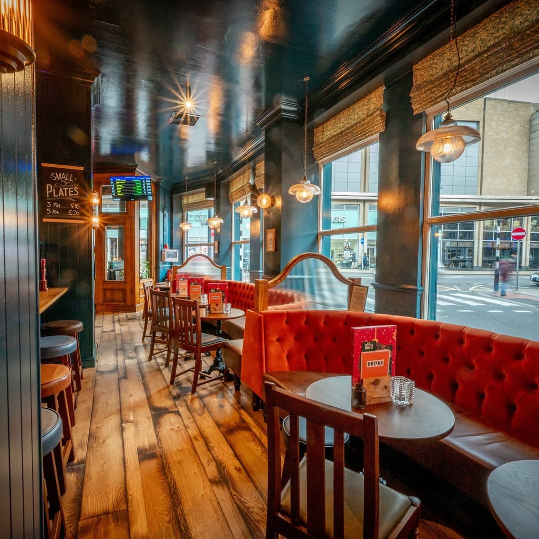 Cozy dining area with plush red booths, wooden tables, and warm lighting, creating an inviting atmosphere.