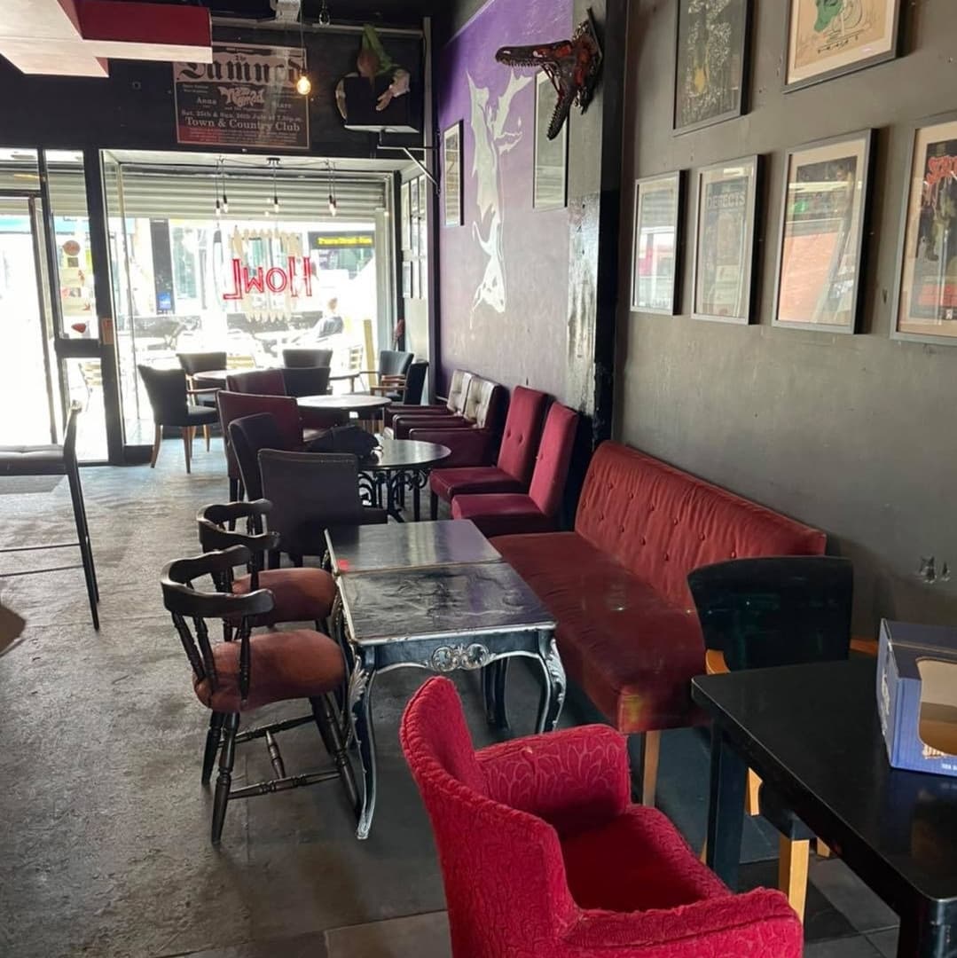 Cozy interior of Howl Bar Leeds featuring eclectic seating, vibrant wall art, and large windows letting in natural light.