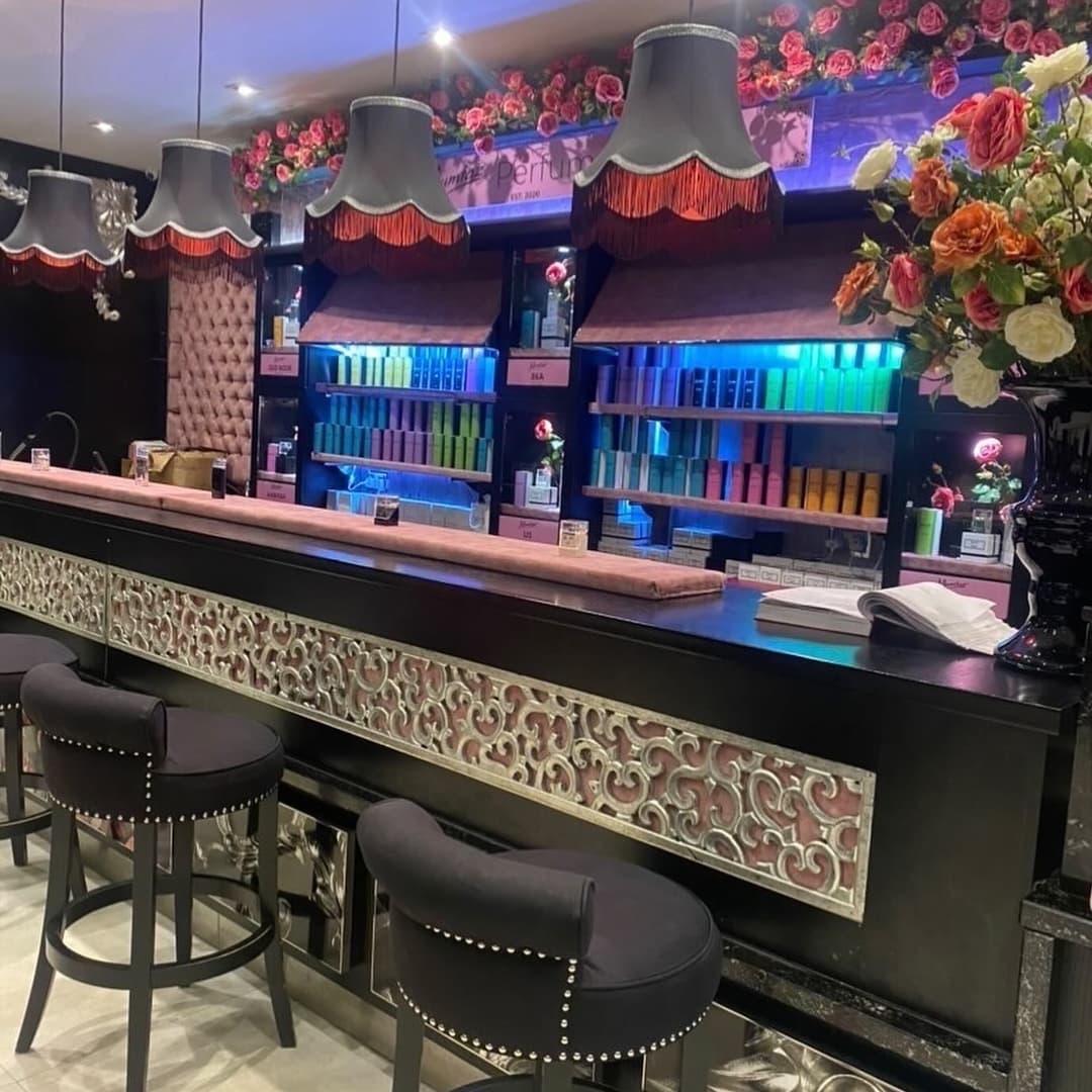 Elegant bar with ornate design, colorful drink displays, plush seating, and floral accents creating a vibrant atmosphere.